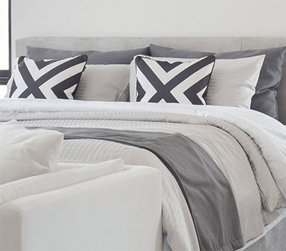 Bed with gray bedspread and navy patterned pillows