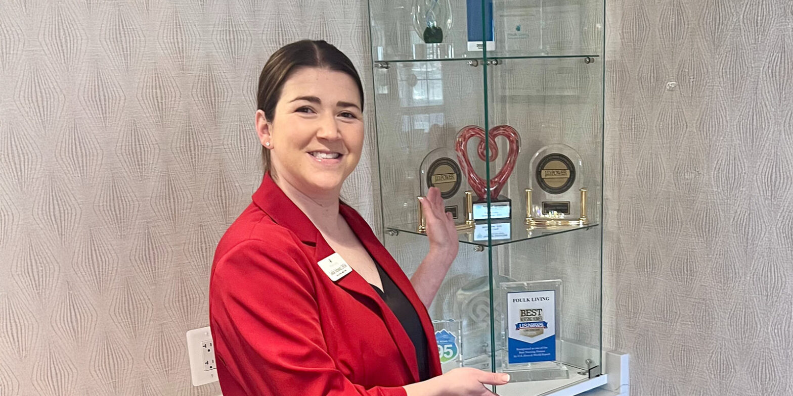 Leslie posing with awards given to Foulk Living