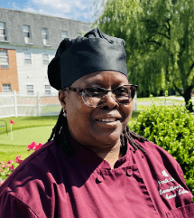 Chef Renee standing outside with a green lawn and building in the background.