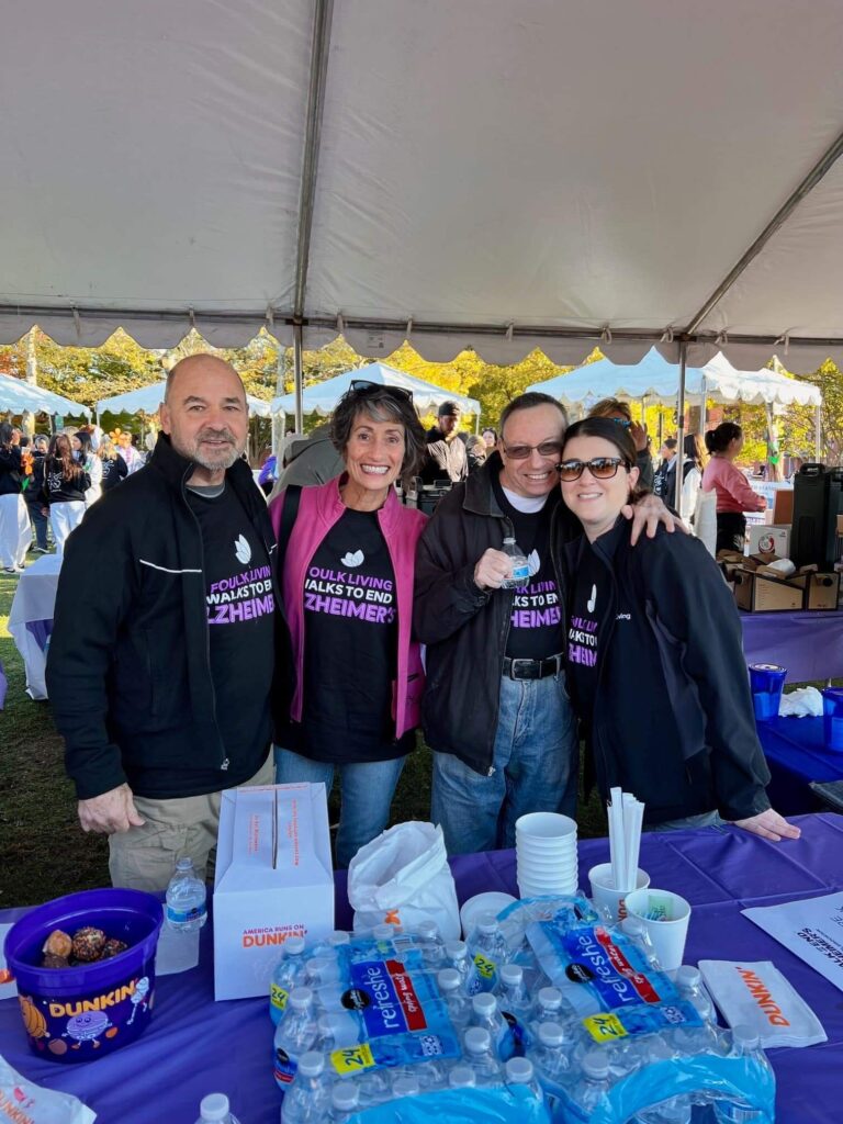 Four people smiling at an Alzheimers charity event under a tent.