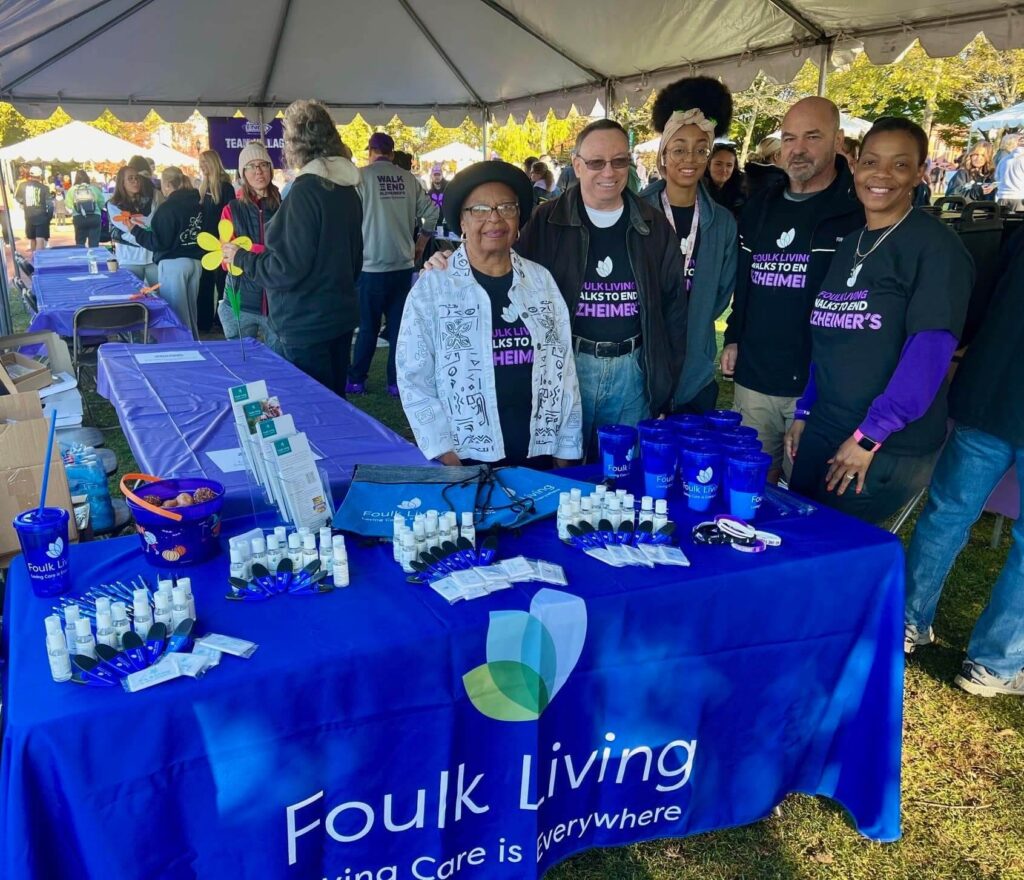 Group at event booth promoting Foulk Living with Alzheimers awareness materials.