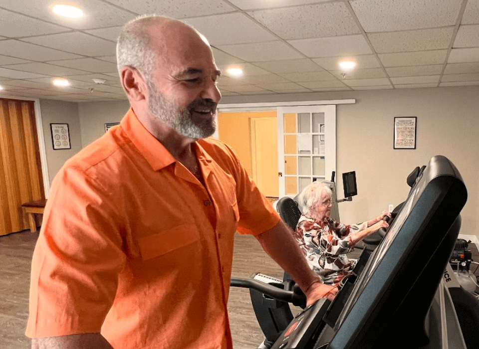 Two residents exercise on equipment in a fitness room, enjoying a healthy lifestyle.